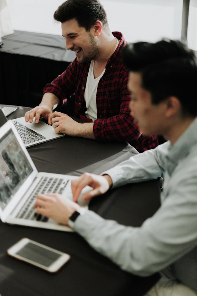 two men working on their laptops happily